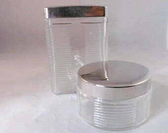 Duo of antique French glass dressing table jars with white metal lids.