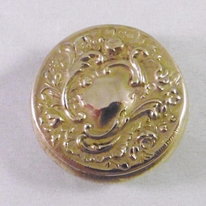 以下が含まれることがあります： 装飾的な花柄が施された、丸い金色の金属製の小物入れ