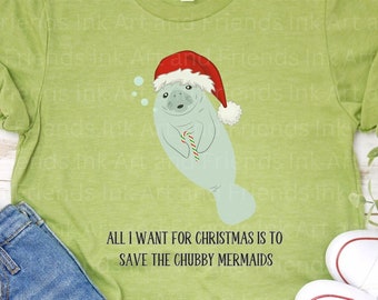 May include: Green t-shirt with a cartoon manatee wearing a Santa hat and holding a candy cane. The text on the shirt reads "All I want for Christmas is to save the chubby mermaids."