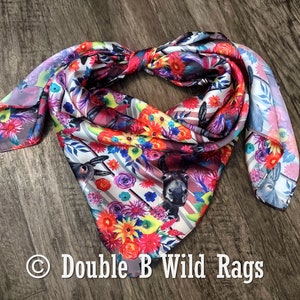 May include: A colorful silk bandana with a floral and donkey print. The bandana is tied in a knot and has a white background with stripes. The text "Double B Wild Rags" is visible in the bottom right corner of the image.
