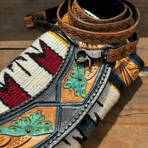 May include: A black leather purse with a woven strap and turquoise floral details. The purse has a silver clasp and a brown leather strap with diamond-shaped stitching.