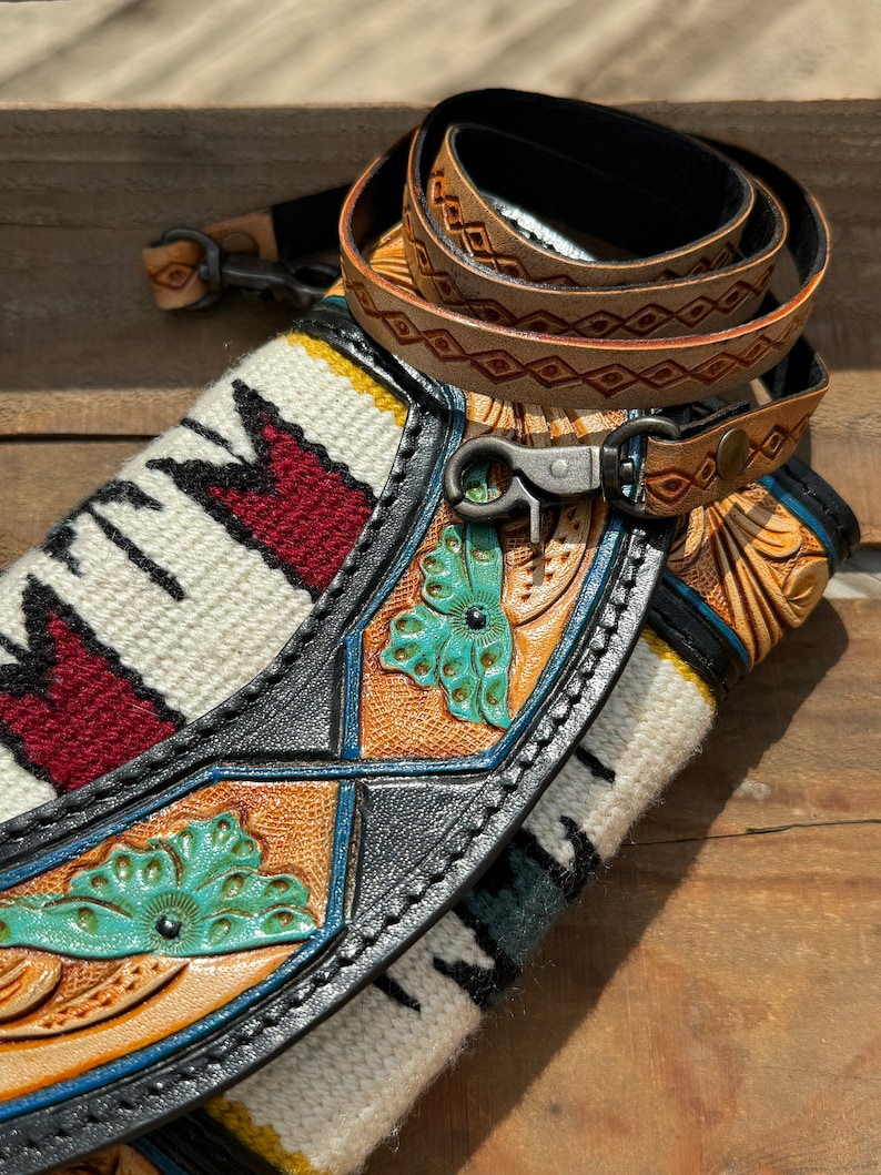 May include: A black leather purse with a woven strap and turquoise floral details. The purse has a silver clasp and a brown leather strap with diamond-shaped stitching.