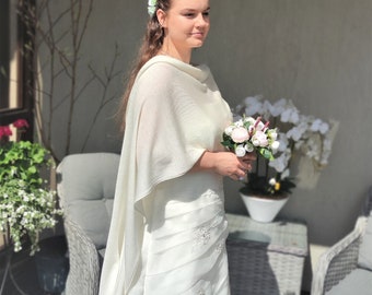 Puede incluir: Una novia con un vestido de novia blanco, una chalina blanca y un ramo de flores rosas y blancas.