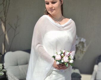 Puede incluir: Una novia con un vestido de novia blanco con una chalina blanca y sosteniendo un ramo de flores rosas y blancas.