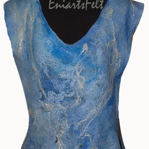 May include: A sleeveless blue and silver felted top with a V-neck and a flowing hemline. The top is made of wool and has a marbled pattern. The text "EmiartsFelt" is visible on the front of the top.