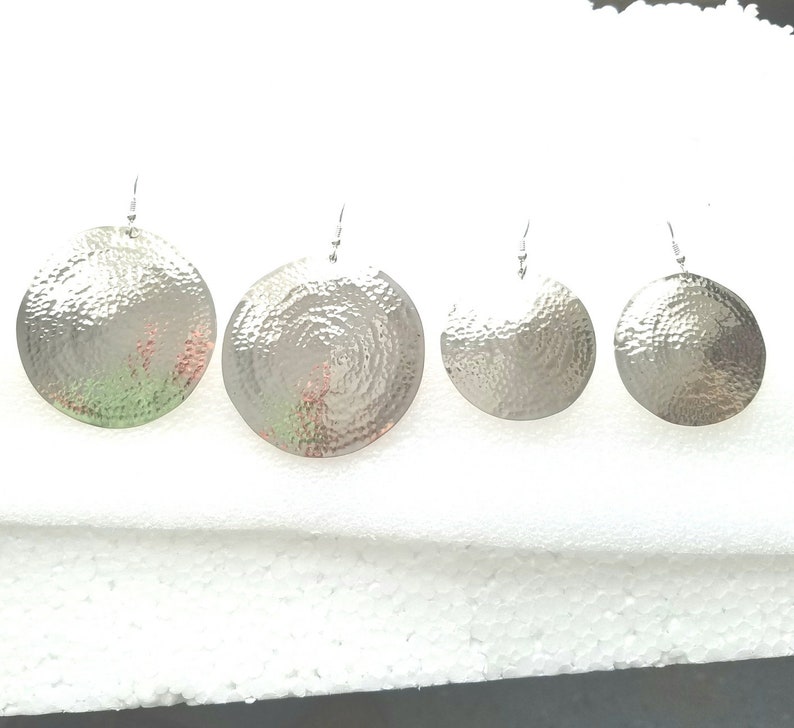 May include: Set of four silver hammered disc earrings of varying sizes. The earrings are round and have a textured surface.
