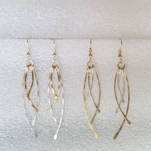 May include: A pair of earrings with a gold and silver design. The earrings are long and dangle, with multiple strands of metal twisted together.