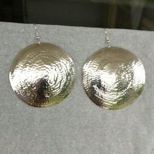 May include: A pair of silver oval-shaped earrings with a hammered texture.