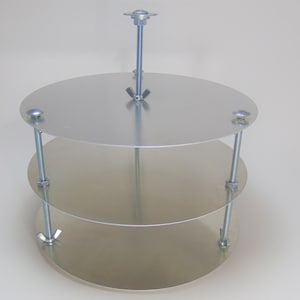 May include: A three-tiered metal cake stand with a silver finish. Each tier is a round plate with a raised edge. The tiers are connected by a central metal rod with a wing nut at the top.
