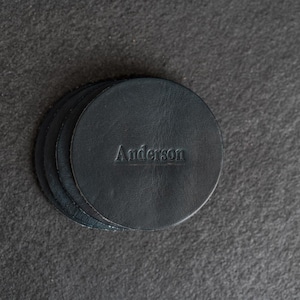May include: A set of four black leather coasters with the name "Anderson" embossed on the top coaster.