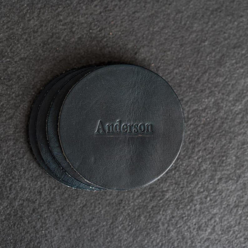 May include: A set of four black leather coasters with the name "Anderson" embossed on the top coaster.