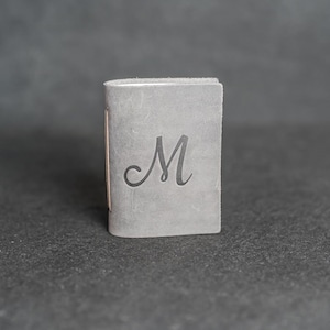 May include: A set of three ceramic mugs with a speckled, matte finish. The mugs are in shades of cream, light gray, and dark gray. Each mug has a simple, minimalist design and a rounded handle.