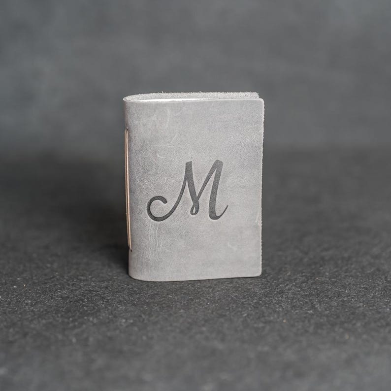 May include: A set of three ceramic mugs with a speckled, matte finish. The mugs are in shades of cream, light gray, and dark gray. Each mug has a simple, minimalist design and a rounded handle.