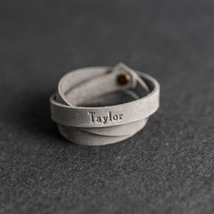 May include: A grey leather bracelet with the name "Taylor" embossed on it.