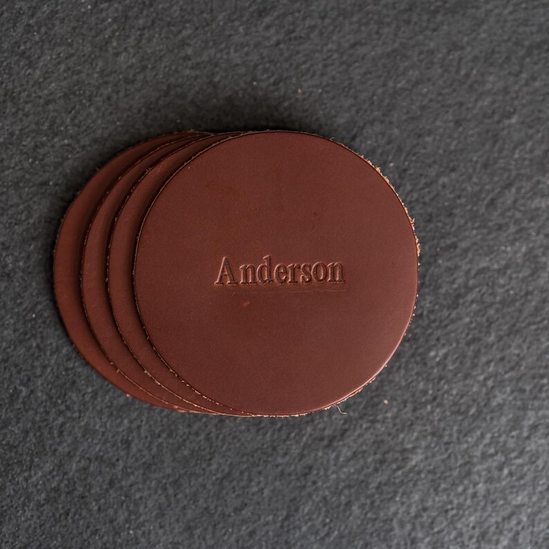 May include: Set of four brown leather coasters with the name "Anderson" embossed on the top.
