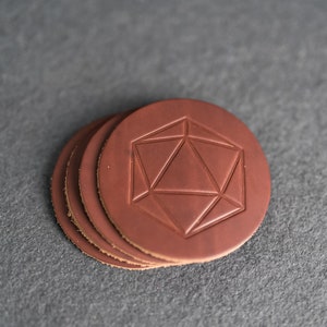 May include: Set of four brown leather coasters with a geometric design embossed on the top.