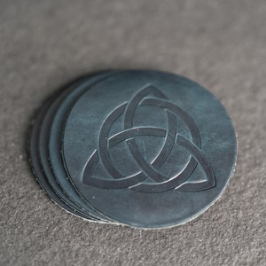 May include: Set of four dark blue leather coasters with a Celtic knot design.