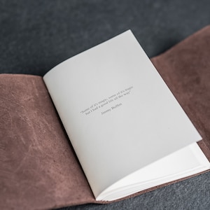 May include: An open leather-bound journal with a white page showing a quote by Jimmy Buffett: "Some of it's magic, some of it's tragic but I had a good life all the way."