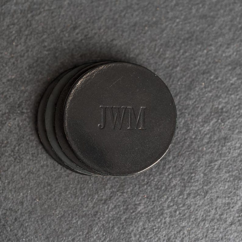 May include: A set of four black leather coasters with the initials "JWM" embossed on the top.