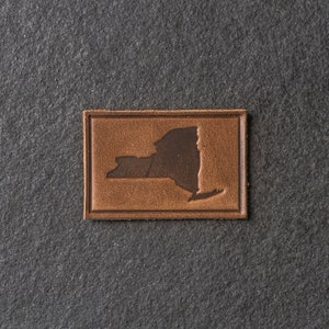 May include: A brown leather patch with the outline of the state of New York.