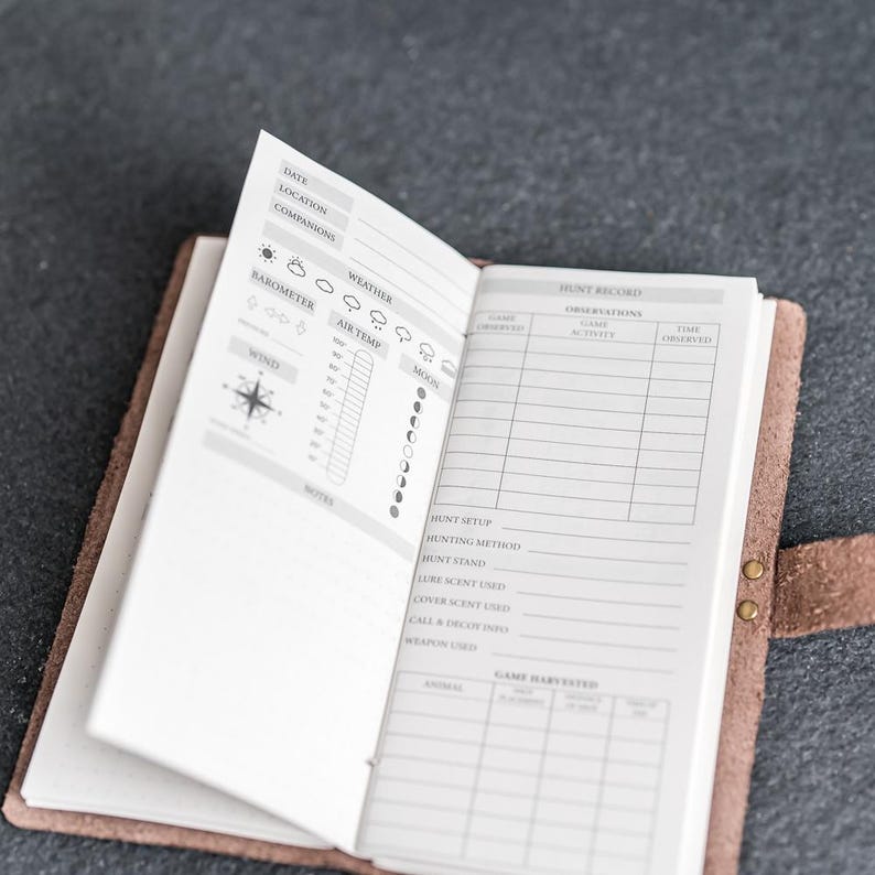May include: Open leather journal with a detailed hunt record. The journal's pages are filled with sections for weather, wind, and moon phases. The right page has sections for observations and game harvested. The journal is secured with a snap closure.
