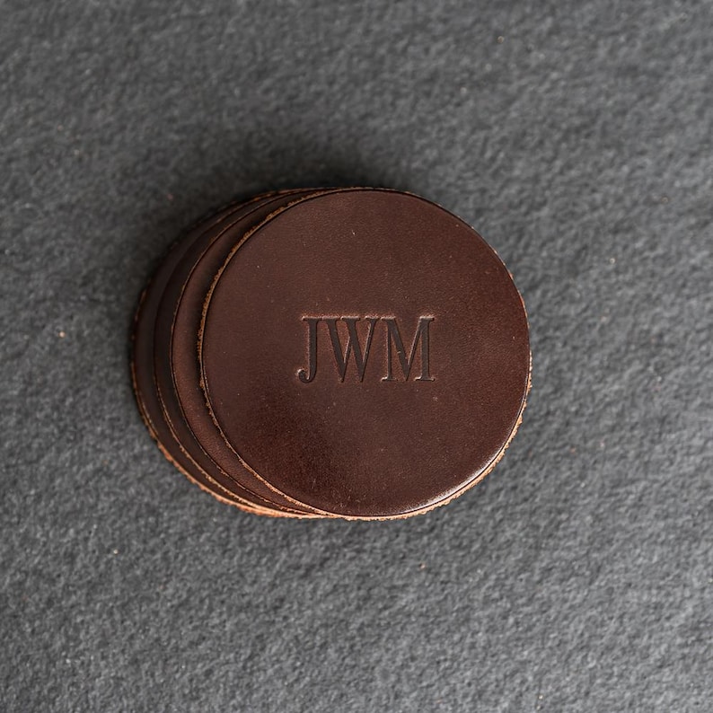 May include: A set of four brown leather coasters with the initials "JWM" embossed in the center.