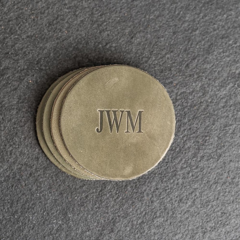 May include: Set of four gray leather coasters with the initials "JWM" embossed in black.