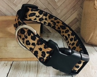 May include: A brown and black leopard print dog collar with a black plastic buckle.