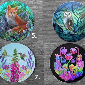 May include: Set of four round stickers featuring nature-themed illustrations. Includes a fox in a forest, an owl on a branch, hummingbirds and flowers, and colorful, abstract plants. Each sticker has the artist's name printed on it.