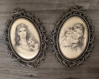 May include: Two oval framed pencil drawings of mothers and children. The frames are silver with ornate designs. The drawings are in black and white.