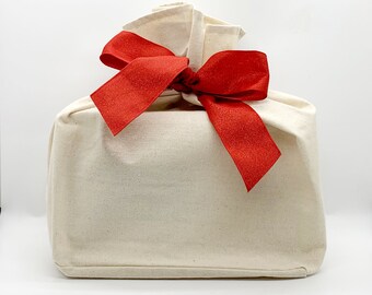 May include: A white fabric gift bag with a large red satin bow.