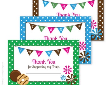 Può includere: Tre biglietti di ringraziamento stampabili con sfondo a pois verde, blu e marrone. Ogni biglietto presenta uno striscione con la parola "Grazie" e un design di biscotti Girl Scout.