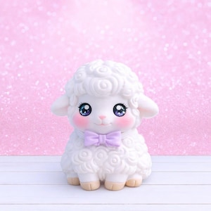 May include: A white lamb figurine with a curly wool texture, large blue eyes, and rosy cheeks. It wears a light purple bow tie. The background is a sparkly pink, and the lamb is on a white surface.