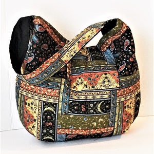 May include: A patchwork tote bag with a black, green, blue, yellow, and orange paisley pattern. The bag has a single strap and a wide opening.