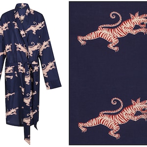 May include: Navy blue robe with a repeating pattern of red and cream-colored tigers. The robe has long sleeves, a wrap-around design, and a matching belt. The fabric is a dark blue with the tiger design repeated across the surface.