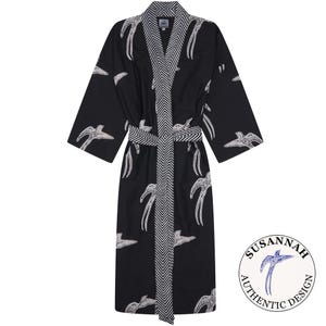 May include: Black robe with a white bird pattern and a chevron design on the trim and belt. The robe has long sleeves and a matching belt. The robe has the text "SUSANNAH AUTHENTIC DESIGN" in a circle on the lower right.