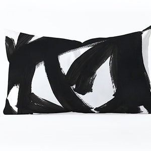 May include: Black and white throw pillow with abstract brushstroke design.