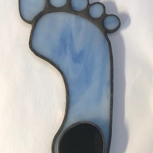 Puede incluir: Un adorno de pie de vidrio coloreado con un dise&ntilde;o azul y blanco y un c&iacute;rculo negro en la parte inferior.