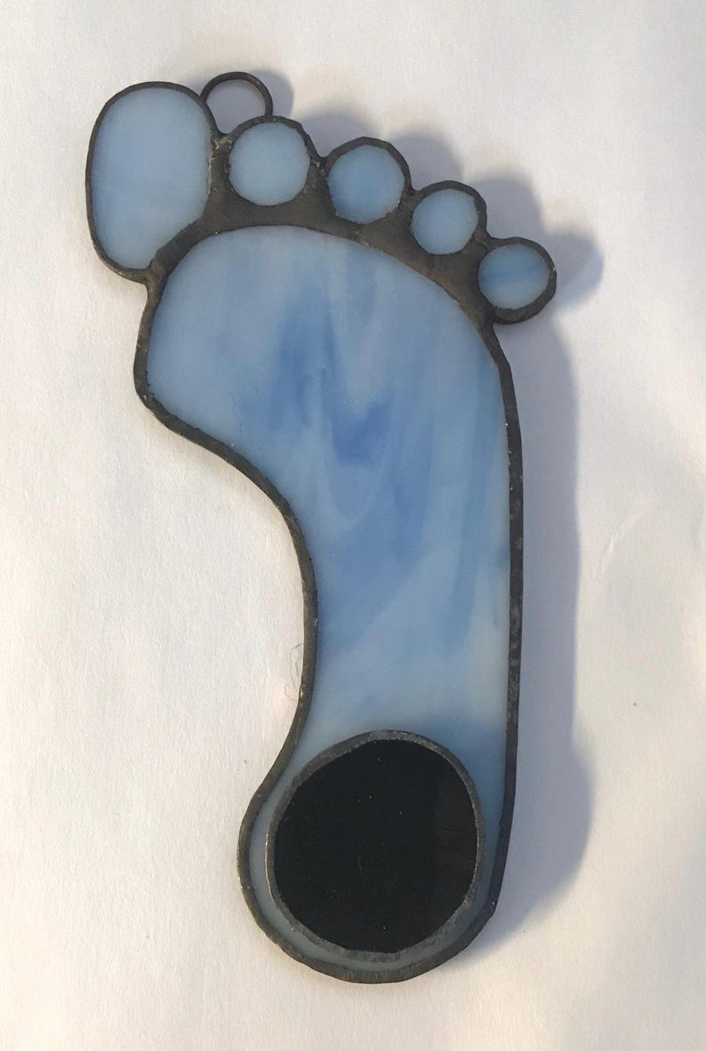 Puede incluir: Un adorno de pie de vidrio coloreado con un dise&ntilde;o azul y blanco y un c&iacute;rculo negro en la parte inferior.