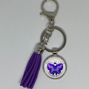 May include: Purple keychain with a silver charm featuring a butterfly with the text "Fibromyalgia Awareness".