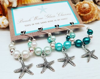 May include: Beach wine glass charms with pearl beads in white, teal, and turquoise. Each charm has a silver starfish pendant. The card in the background reads "Beach Wine Glass Charms".