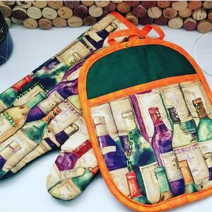 May include: A quilted oven mitt and pot holder set. The set features a wine bottle design with green, purple, and red bottles on a beige background. The pot holder has a green top and orange trim.