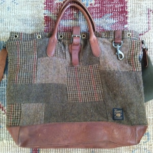 May include: A brown leather and tweed patchwork tote bag with a buckle closure and a detachable shoulder strap. The bag has a brown leather bottom and a label with the text "Porter" on the side.