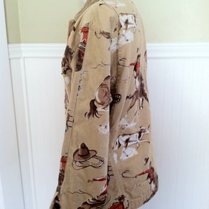 Pu&ograve; includere: Giacca beige con stampa a tema cowboy con cowboy, cavalli e un cappello da cowboy. La giacca ha un colletto in velluto a coste e una chiusura con bottoni. Il tessuto &egrave; di colore beige chiaro con un motivo ripetuto di immagini di cowboy.