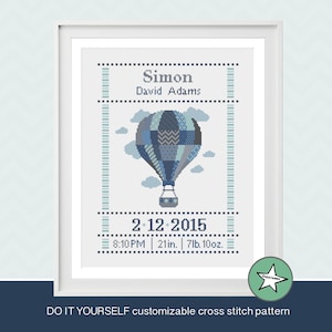 May include: A cross stitch pattern featuring a blue and grey hot air balloon with clouds, the text "Simon David Adams", and the date "2-12-2015" with the time "8:10PM", length "21in", and weight "7lb 10oz".