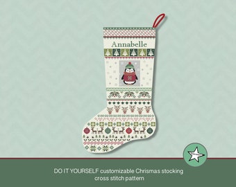 May include: A white Christmas stocking with a green, red, and white Scandinavian-style pattern. The stocking has a penguin wearing a red sweater and a green hat in the center. The name "Annabelle" is stitched at the top of the stocking.