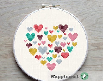 Puede incluir: Un bastidor de bordado de punto de cruz con un diseño de corazón compuesto por corazones pixelados de varios colores. Los colores incluyen rojo, turquesa, amarillo, rosa, gris y burdeos. La palabra "Happinesst" está impresa en la parte inferior.