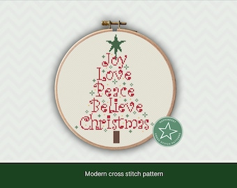 Może przedstawiać: Biały wzór do haftu krzyżykowego z motywem choinki. Choinka jest ozdobiona napisami "Joy", "Love", "Peace", "Believe" i "Christmas".