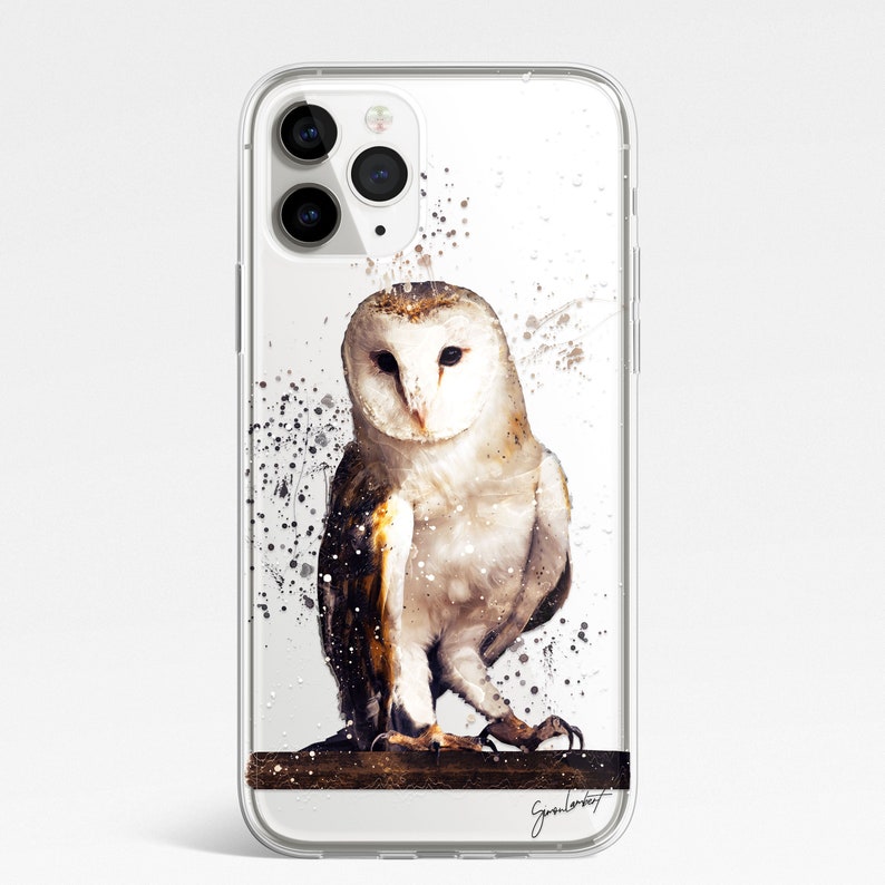May include: Clear phone case featuring a watercolor painting of a barn owl. The owl has white and brown feathers and is perched on a branch. Splatter art in black and brown surrounds the owl. The artist's signature is at the bottom.