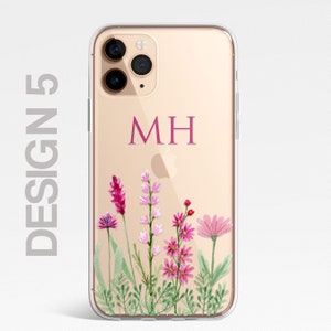 Op de afbeelding: Een transparante telefoonhoes met een gouden achtergrond en een bloemenontwerp. De hoes heeft een roze monogram "MH" op de achterkant.